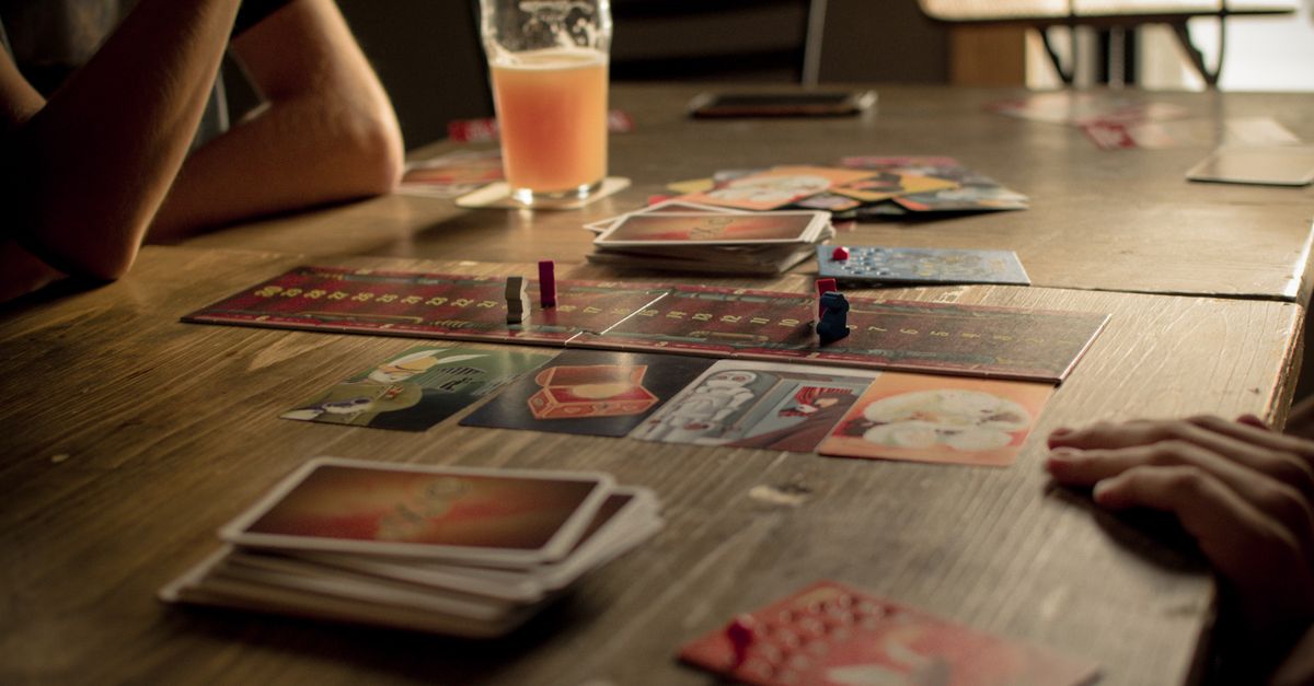 People playing a board game at a café table, capturing leisure and social interaction.
